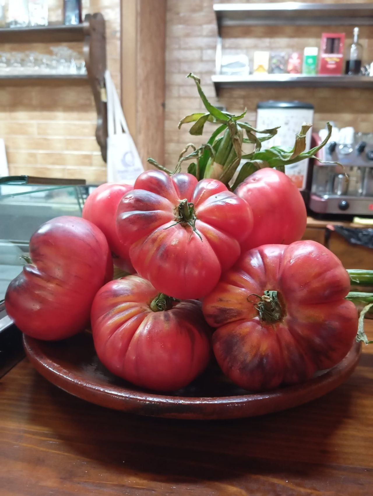 A rustic clay plate piled with ripe heirloom tomatoes from the garden, on El Molino's bar