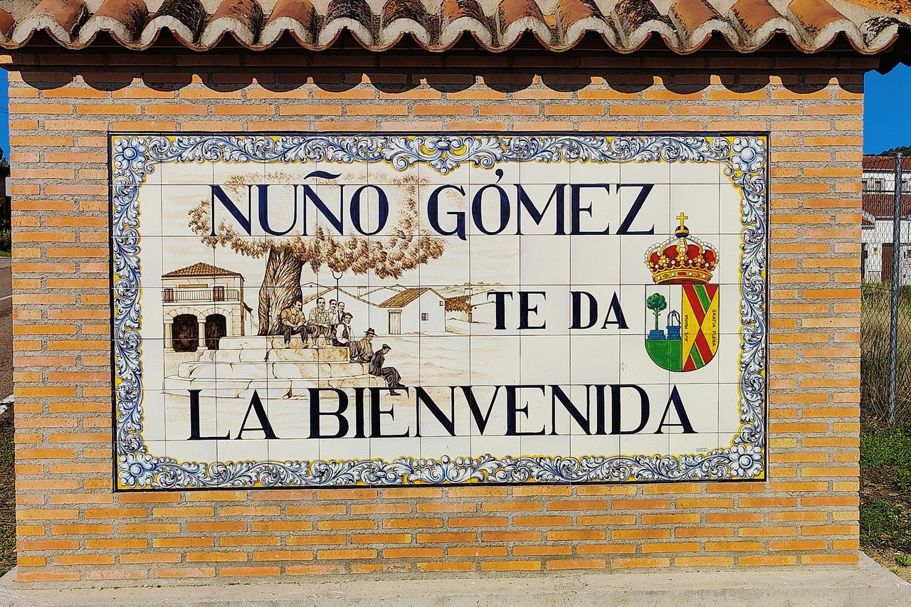 Tiled welcome sign at the entrance of Nuño Gómez (Toledo), reading 'Nuño Gómez te da la bienvenida'